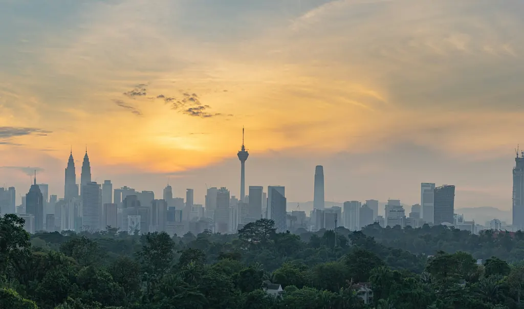 Kuala Lumpur skyline at dusk with the city’s towers against a warm sky
