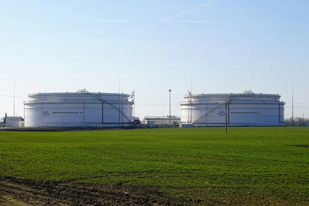 Two large white storage tanks on open ground under a clear sky
