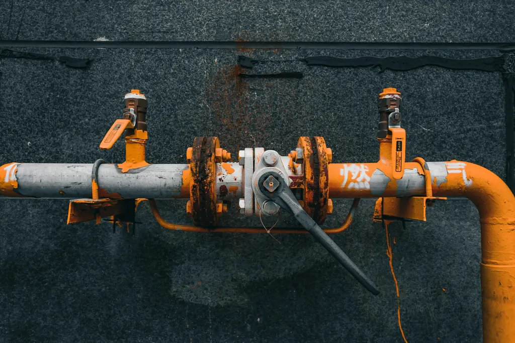Orange-painted pipework and valve assembly on a dark wall